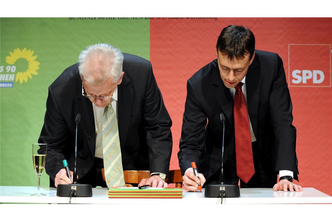 2011: Der designierte baden-württembergische Ministerpräsident Winfried Kretschmannund der designierte Minister für Finanzen und Wirtschaft, Nils Schmid (SPD), schreiben  gemeinsam ihre Namen auf den Tisch. (Archivbild).