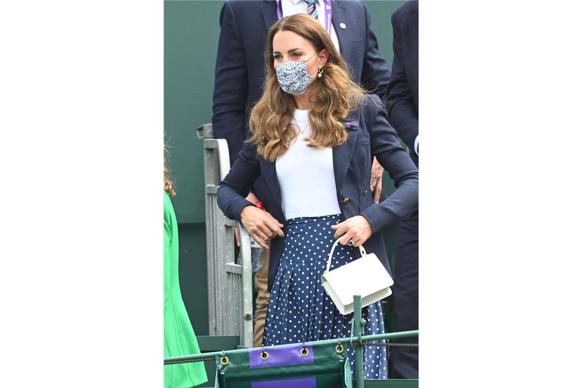 2021: Wimbledon ist nach einem Jahr Zwangspause zurück – aber die Corona-Pandemie erfordert besondere Sicherheitsmaßnahmen. Blümchen-Maske zum Beispiel, die die Herzogin zu einem blauen Pünktchen-Rock von Alessandra Rich und einem dunkelblauen Smythe-Blazer kombinierte.