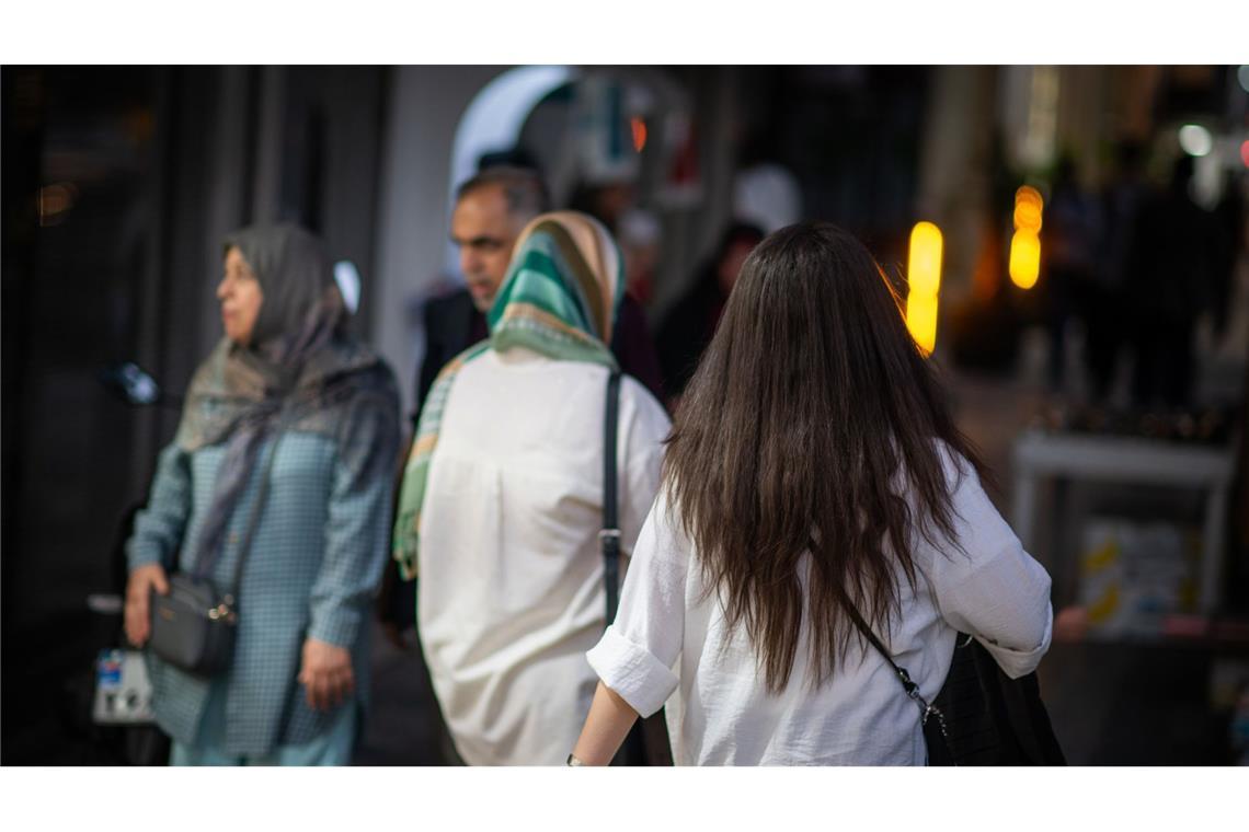 Neues Kopftuchgesetz sorgt landesweit für Empörung 2023: Eine Frau läuft in Teheran mit offenen Abend am Abend eine Straße entlang.