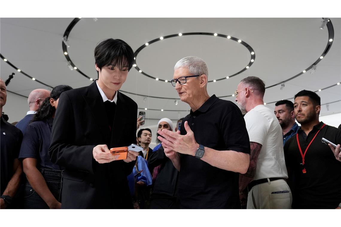 2026: Apple Chef Tim Cook (M) steht unter Druck, ein neues großes Ding - "One More Thing" abzuliefern.