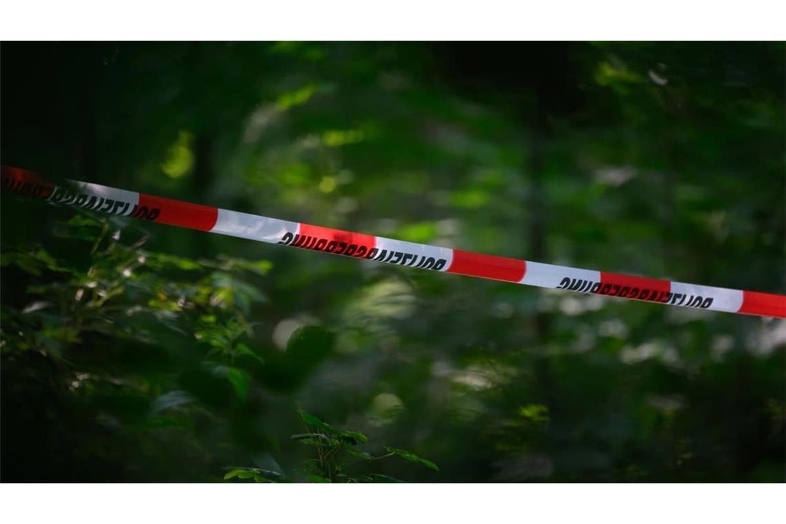 Absperrband der Polizei ist in einem Wald gespannt. (Symbolbild)