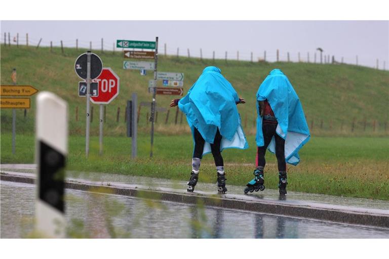 Alles eine Frage der richtigen Kleidung -  Zwei Inline-Skaterinnen fahren im strömenden Regen im bayerischen Roßhaupten.