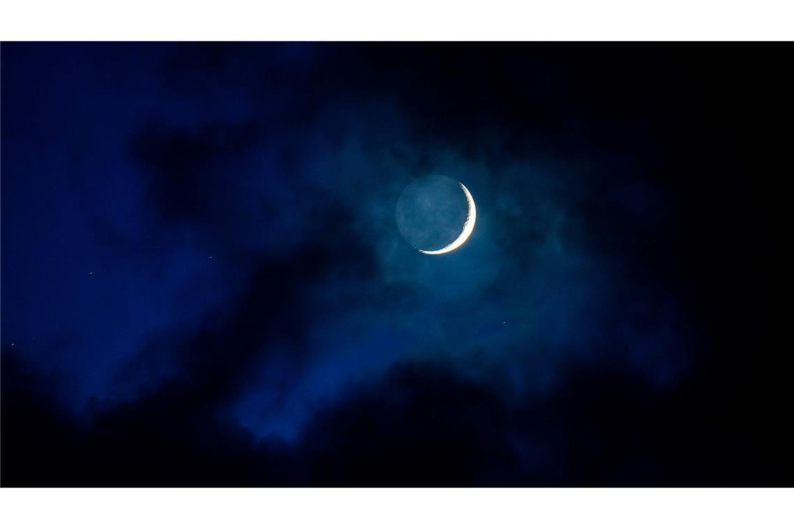 Bilder des Tages Als schmale Sichel scheint der Mond am Abendhimmel über Mecklenburg-Vorpommern hinter einer Wolkenlücke hervor.