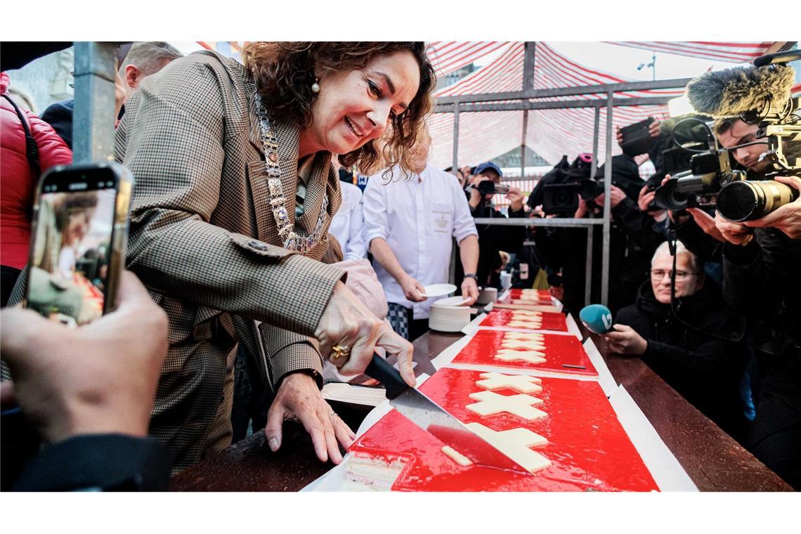 Amsterdams Bürgermeisterin Femke Halsema schneidet die lange Torte an.