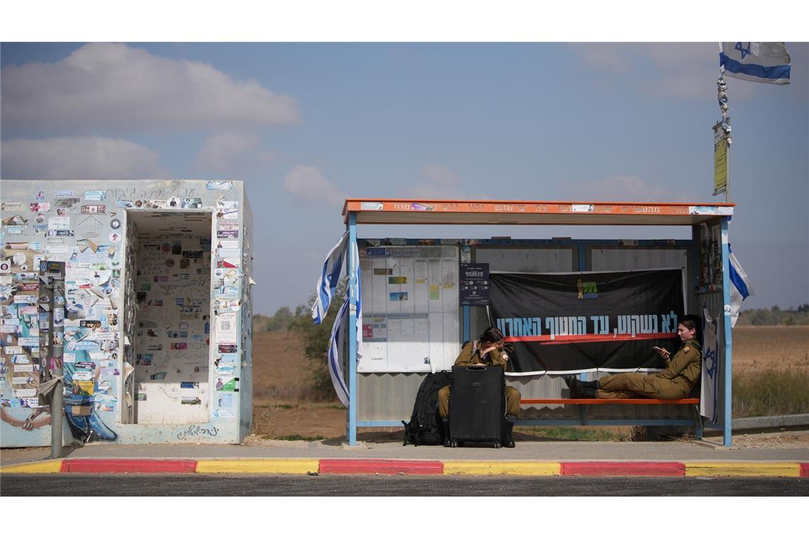 An einem Busbahnhof nahe der Grenze zum Gazastreifen warten israelische Soldatinnen auf den Transport.