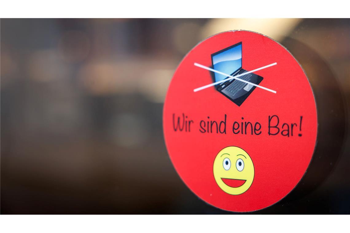 Warum Cafés Laptops verbannen An einer Scheibe der Café-Bar 8tto Grammi in Bayreuth weist ein Schild auf das Verbot von Laptops hin.