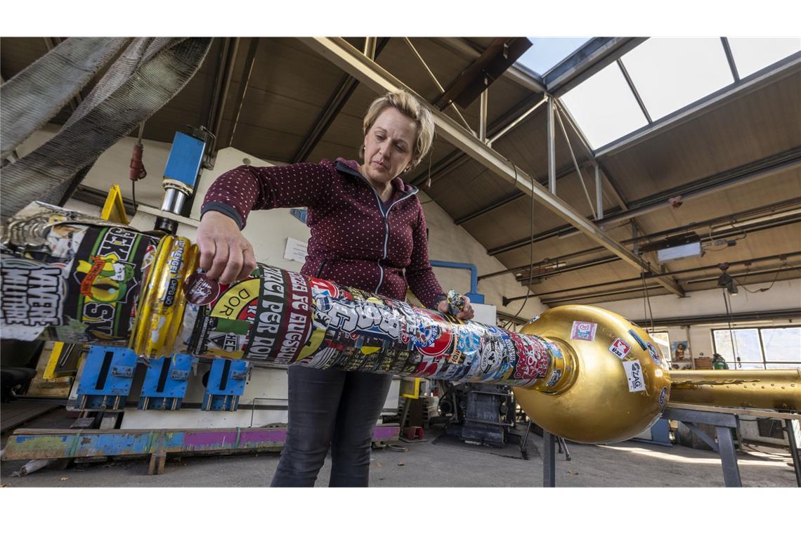 Andrea Würzinger entfernt Aufkleber vom Zugspitz-Gipfelkreuz, das anschließend in ihrem Kunstschmiede-Betrieb restauriert wird.