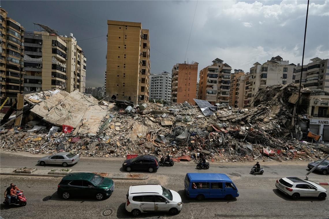 Anwohner fahren an den Trümmern zerstörter Gebäude in Dahija, einem südlichen Vorort von Beirut, Libanon, vorbei.