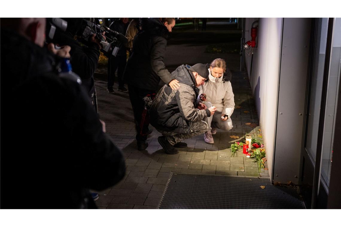 Nach Fund von drei Leichen wird mutmaßlicher Täter gesucht Anwohner legen Blumen und Kerzen nieder.