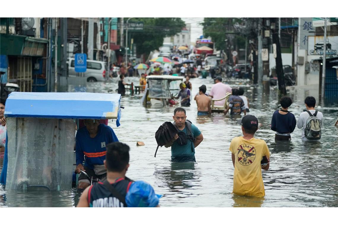 Anwohner waten durch eine überschwemmte Straße auf den Philippinen.