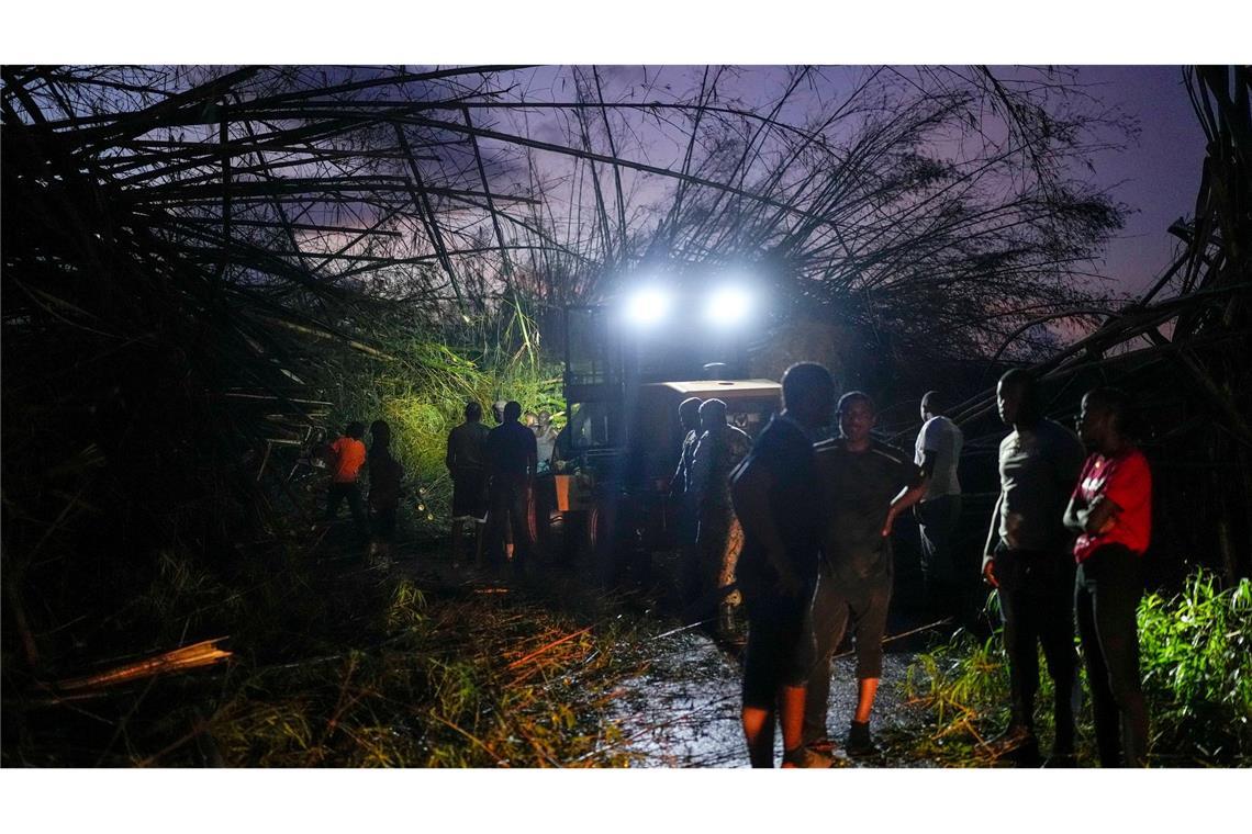 Arbeiter räumen umgestürzte Bäume und Trümmer beiseite.