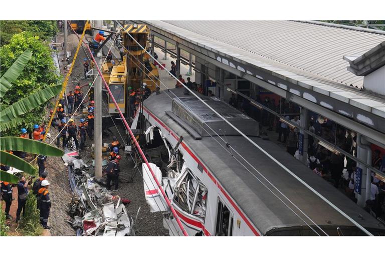 Arbeiter setzen eine schwere Maschine ein, um die Trümmer eines Zuges nach einer Kollision in Bekasi, Indonesien, zu beseitigen.