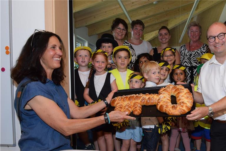 Architektin Margit Munz (links) überreicht zur Einweihung einen Hefezopf an Armin Mößner. Die Kinder verkleideten sich für eine Aufführung als Bauarbeiter. Foto: Elisabeth Klaper