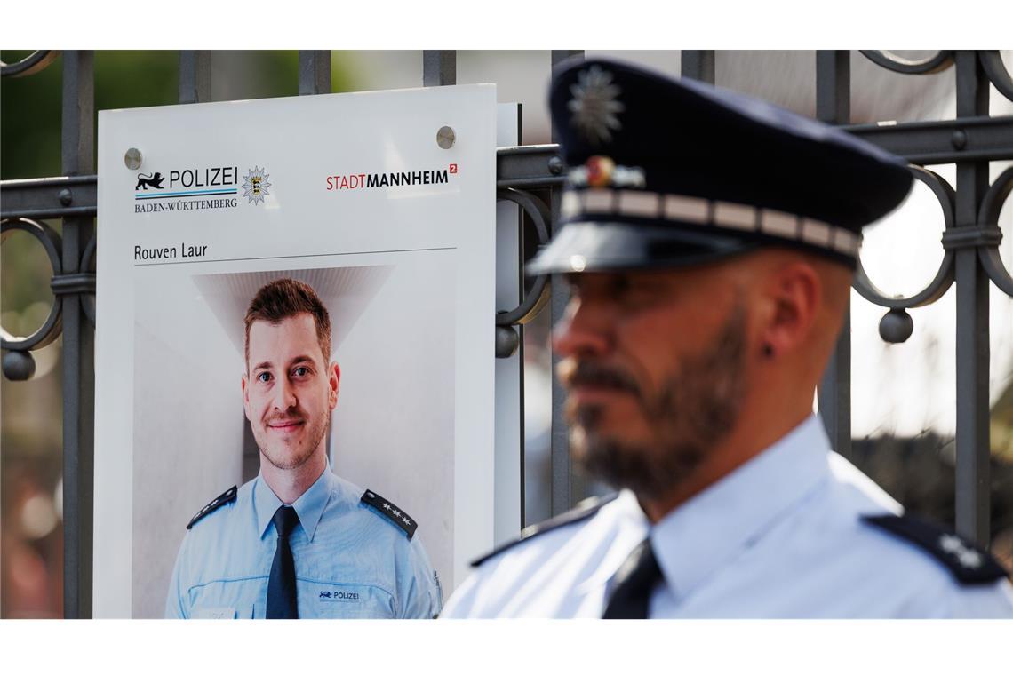 Archivbild: Ein Polizist steht neben einer Gedenktafel für Rouven Laur.