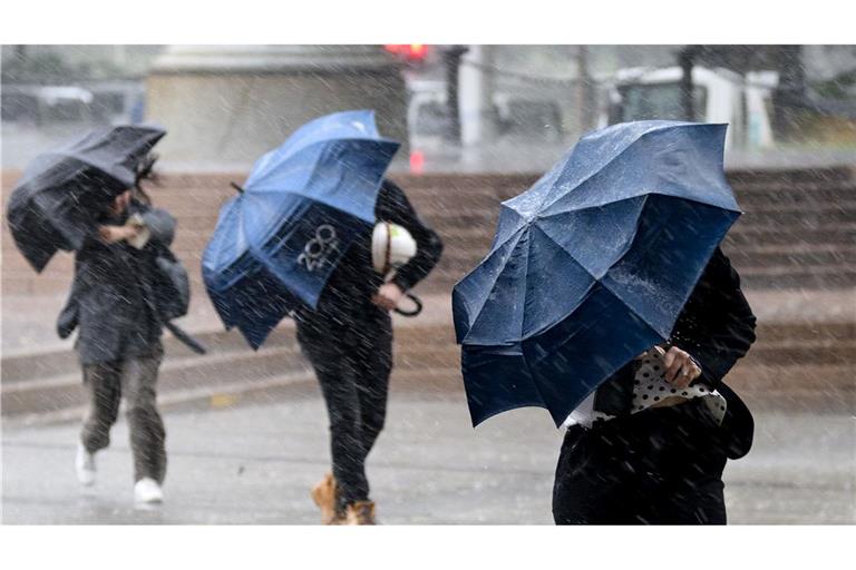 Auch in Australien scheint nicht immer die Sonne: Passanten in Sydney schützen sich mit Schirmen vor starkem Regen.