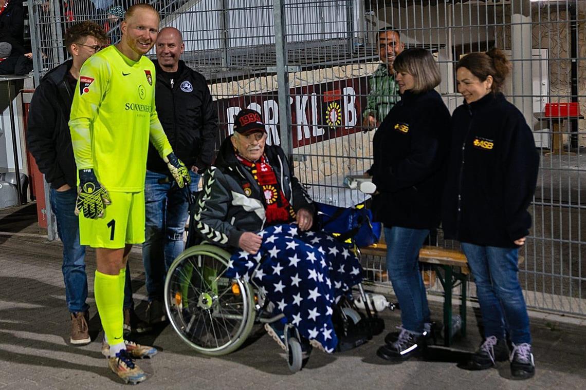 Jakob Mesch: „Die Meisterschaft will ich noch erleben“ Auch schwer erkrankt lässt sich Jakob Mesch das Derby nicht entgehen. Dank der Hilfe von Arzt Johannes Kirsch (leicht verdeckt), Sohn Joachim und den Begleiterinnen vom Wünschewagen ist er zur großen Freude von SG-Torhüter Maximilian Reule beim 1:1 live dabei. Foto: privat