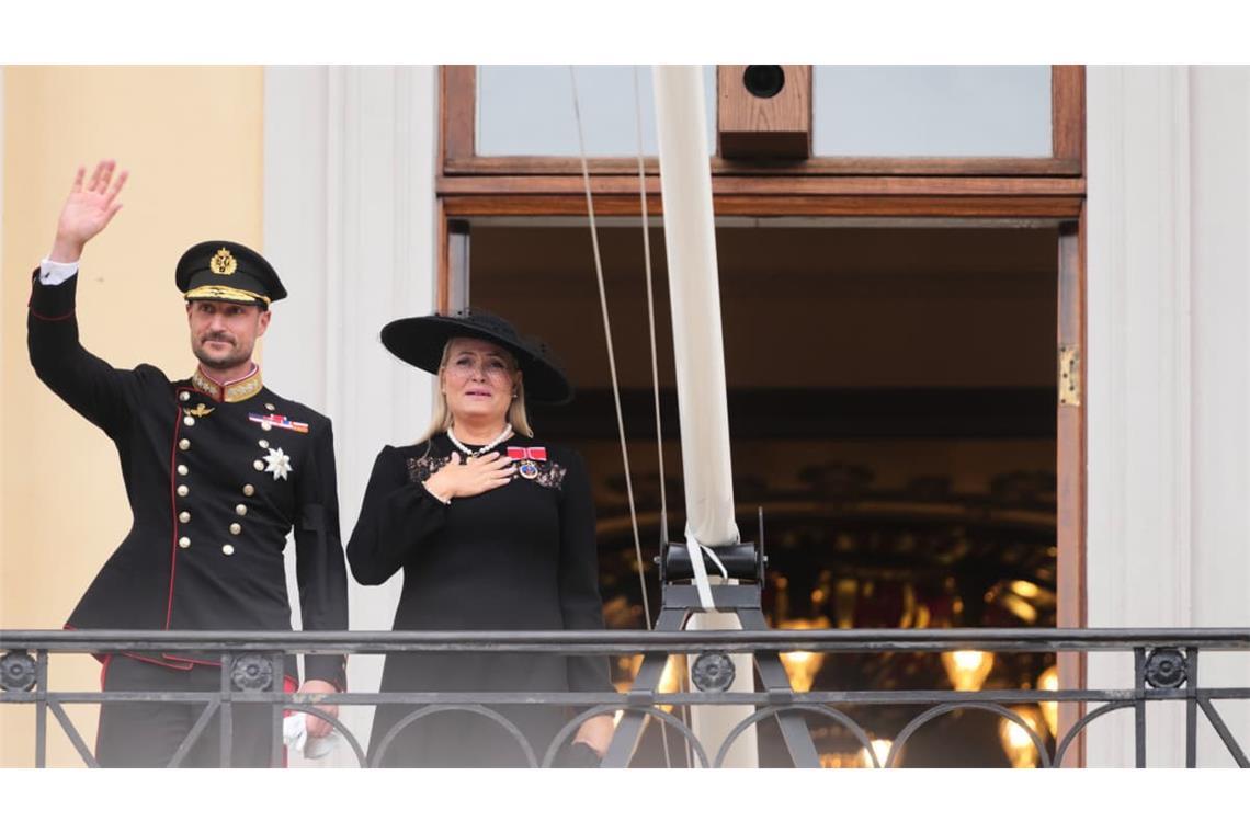 Auf dem Balkon des Königlichen Schlosses zeigt sich das neue Königspaar den Menschen in Oslo: Während König Haakon VIII. der Menge zuwinkt, legt Königin Mette-Marit sichtlich bewegt die Hand auf ihr Herz.