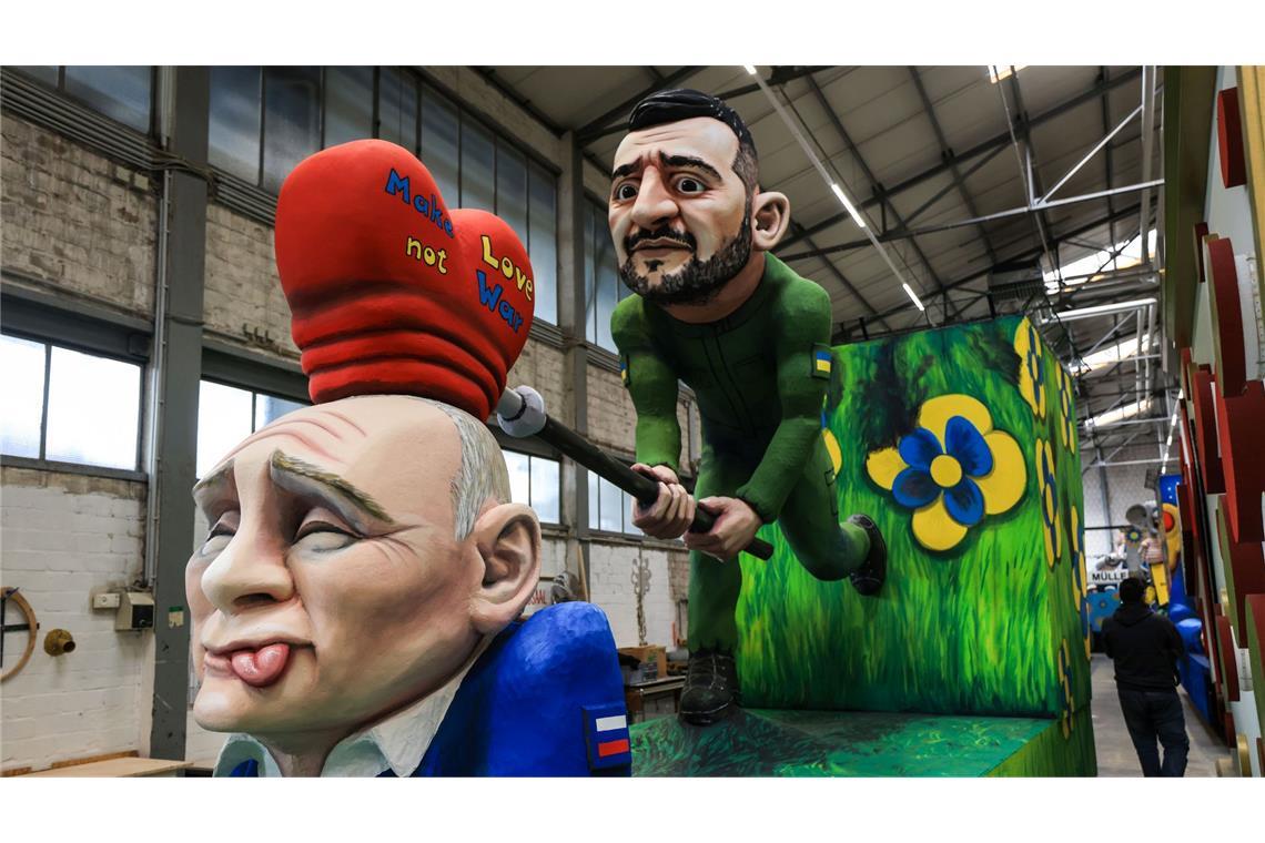 Trump, Musk und Putin im Kölner Rosenmontagszug Auf einem der Wagen versucht der ukrainische Präsident Wolodymyr Selenskyj, dem russischen Präsidenten Wladimir Putin die Botschaft "Make Love not War" einzuhämmern.