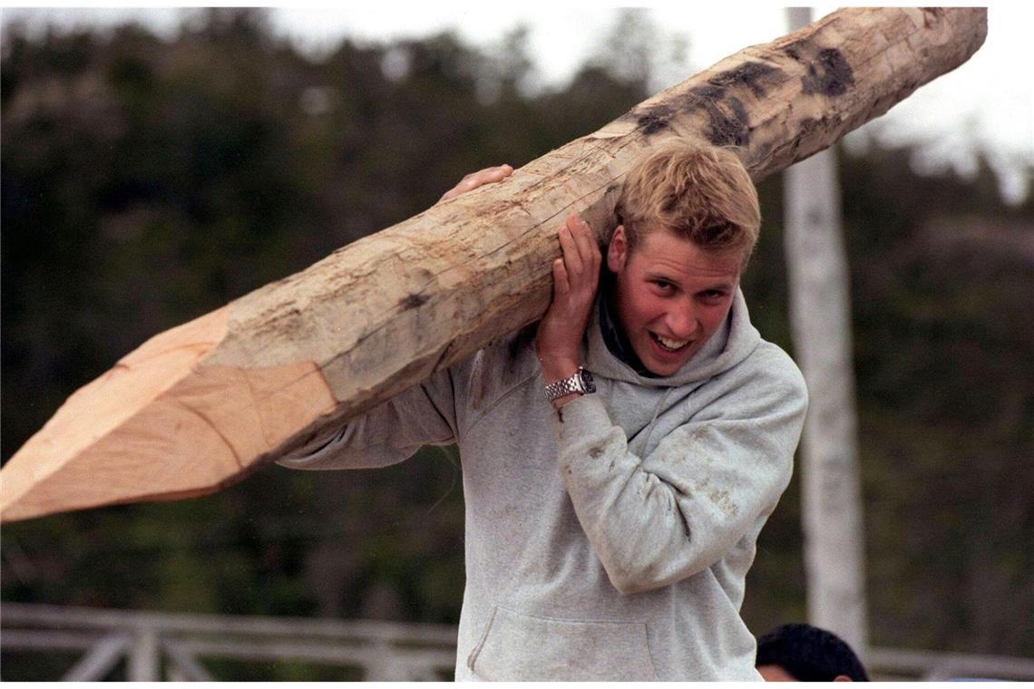Aufnahme vom Dezember 2000, auf der der britische Prinz William während seiner Raleigh-International-Expedition im südchilenischen Dorf Tortel einen Baumstamm trägt, der für den Bau von Holzstegen zwischen den Gebäuden verwendet wurde.