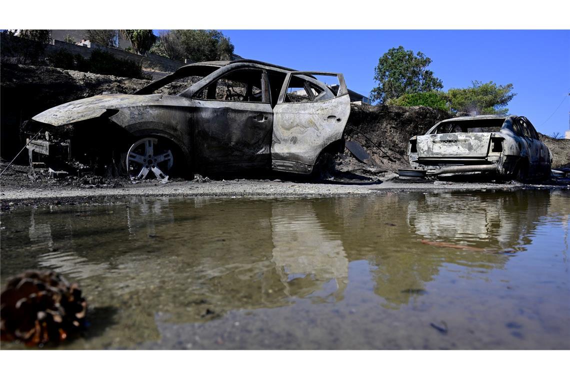 Ausgebrannte Autos spiegeln sich im Wasser nach einem Waldbrand in dem Dorf südöstlich von Athen.