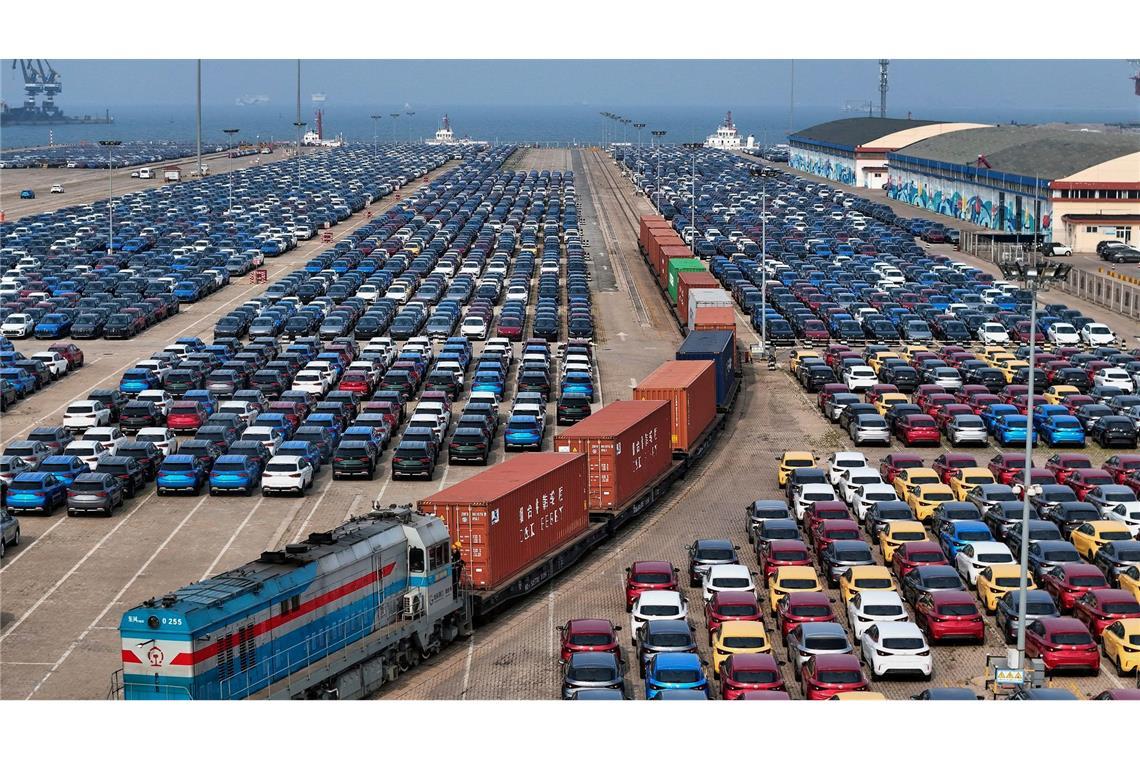 Bilder des Tages Außenhandel China - Ein Güterzug fährt in der ostchinesischen Provinz Shandong an neuen Autos vorbei, die in einem Hafen auf ihre Verschiffung warten.
