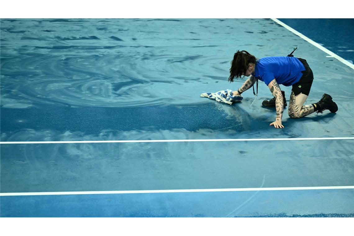 Australian Open: Eine Person trocknet den Platz mit einem Handtuch, nachdem das Spiel aufgrund des Regens unterbrochen wurde.