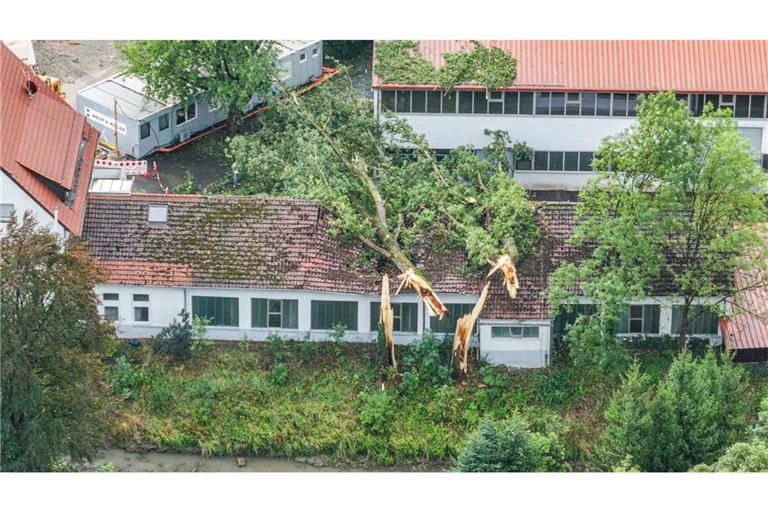 Bäume liegen nach einem schweren Unwetter auf einem Gebäude (Luftaufnahme mit Drohne).