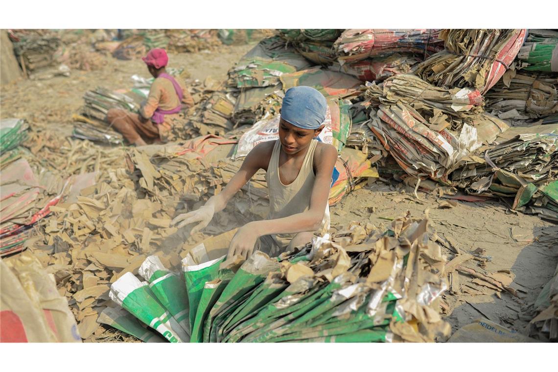 Bilder des Tages Bangladesch: Kinder sortieren inmitten von Zementstaub gebrauchte Zementsäcke am Ufer des Surma-Flusses.