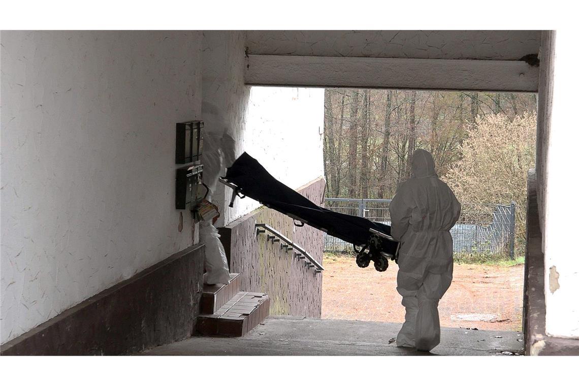 Beamte der Spurensicherung bringen eine Trage in ein Wohnhaus.