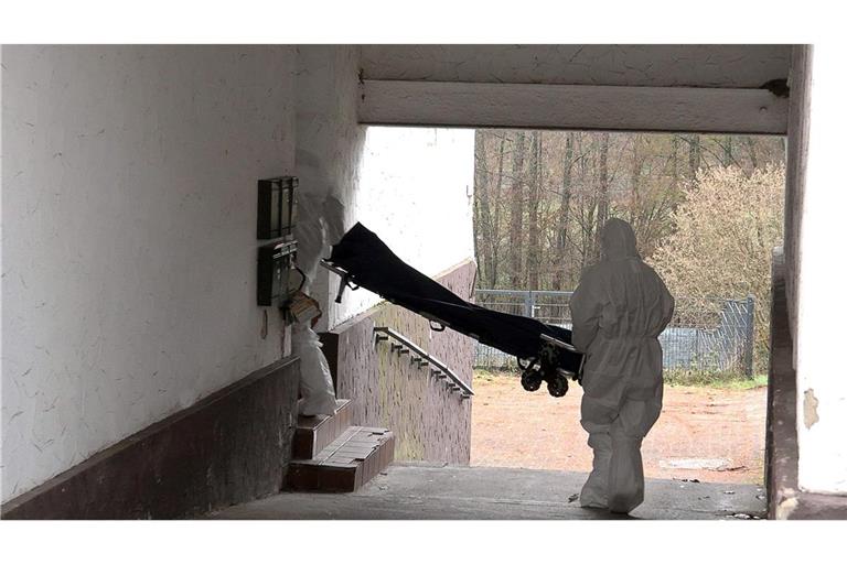 Beamte der Spurensicherung bringen eine Trage in ein Wohnhaus.