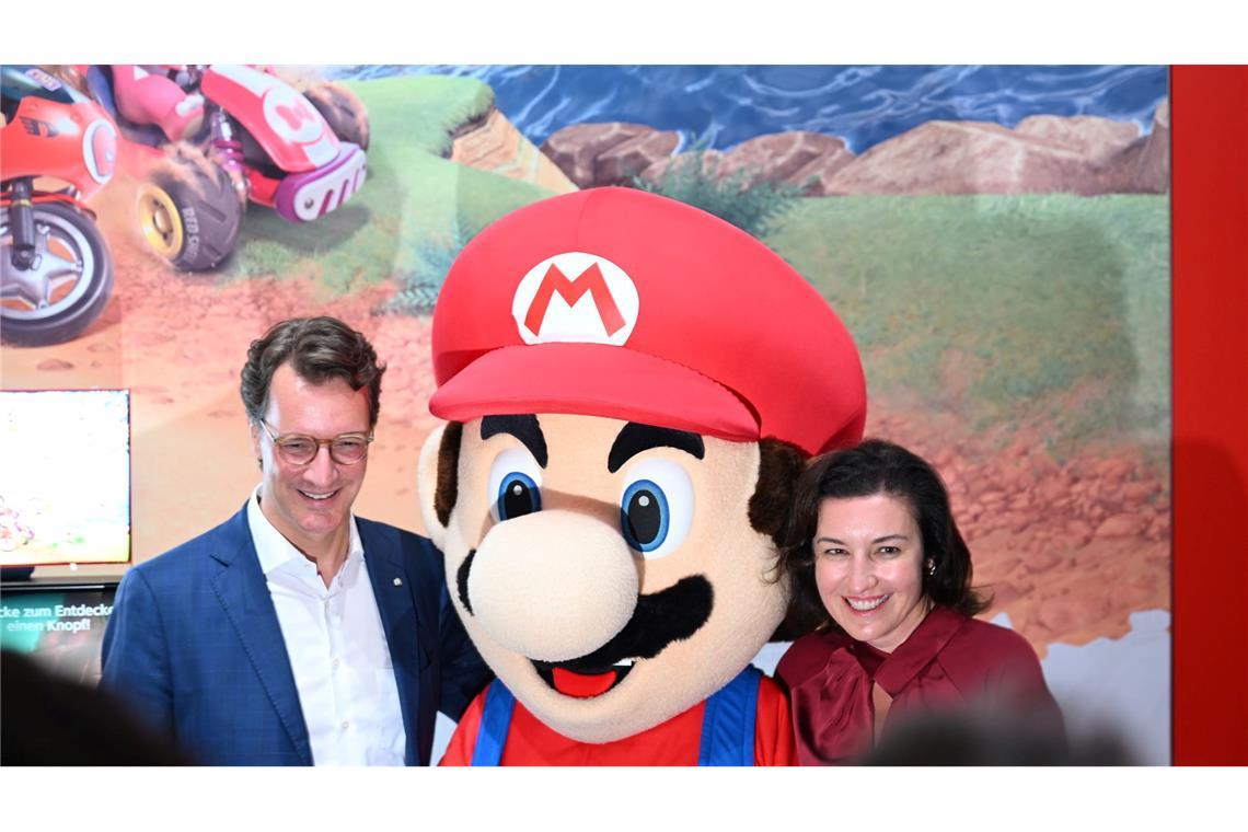 Beim Messerundgang über die Gamescom kam der Tross von Politikern auch beim Messestand von Nintendo vorbei, hier stehen NRW-Ministerpräsident Hendrik Wüst (CDU) und Bundesforschungsministerin Dorothee Bär (CSU) neben einer Mario-Plüschfigur.
