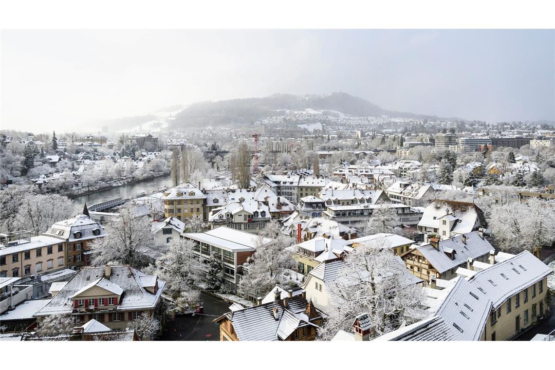 Bern im Winterkleid: Schnee auf Dächern und Bäumen, der Gurten taucht aus leichtem Nebel auf