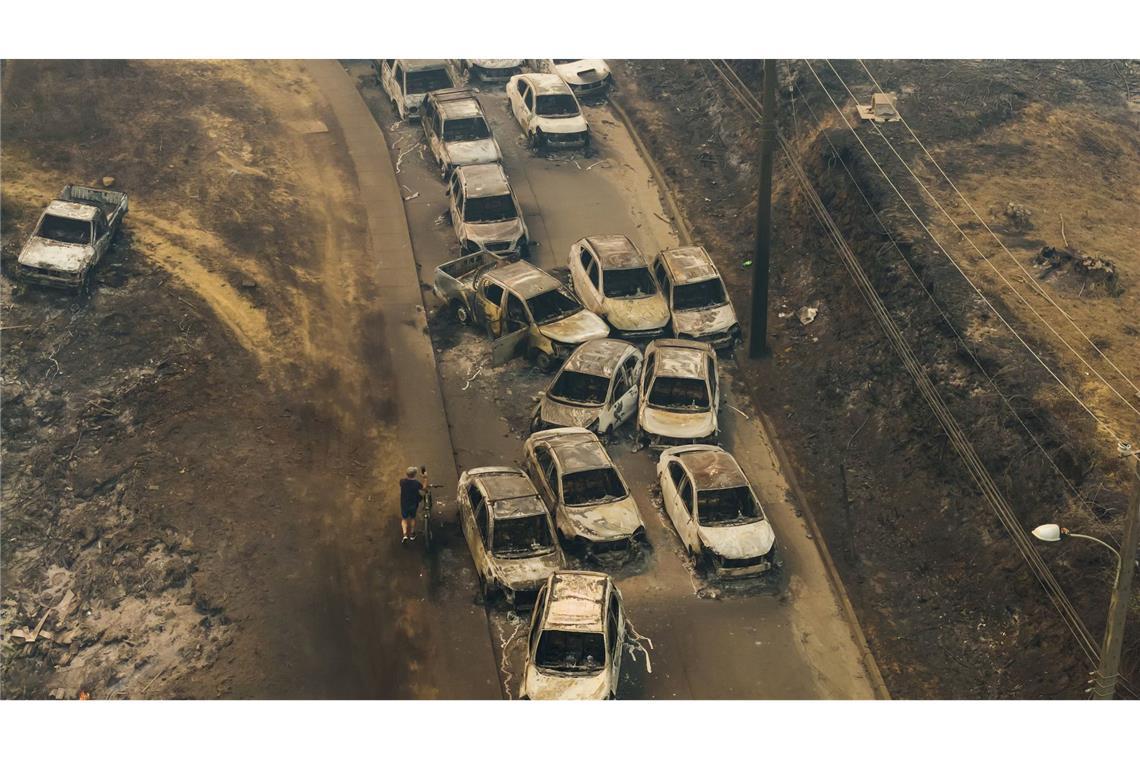 Beschädigte Fahrzeuge säumen eine Straße, nachdem Waldbrände Wohngebiete in Lirquen in Chile verwüstet haben.