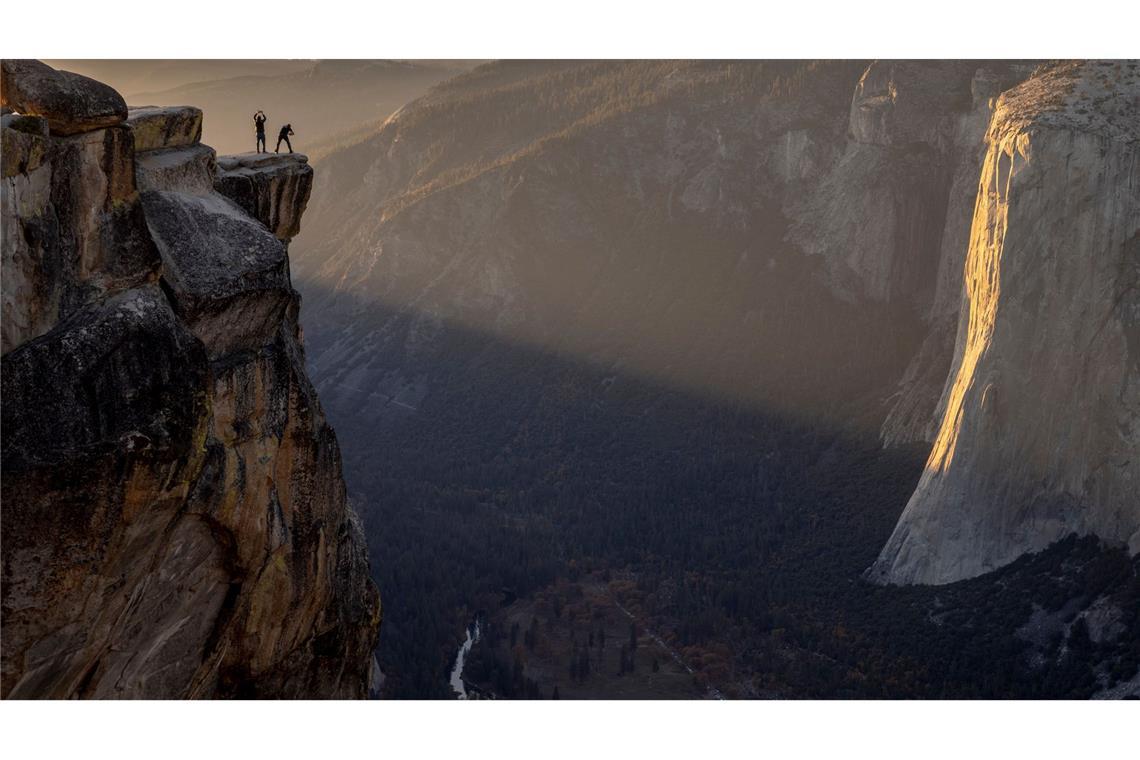 Besucher posieren für ein Foto auf einem Felsvorsprung in der Nähe von Taft Point im Yosemite Nationalpark in den USA.