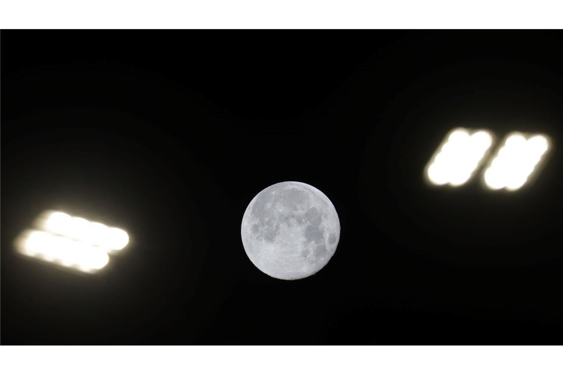 Blick auf den Mond zwischen Straßenlaternen in Riedlingen.