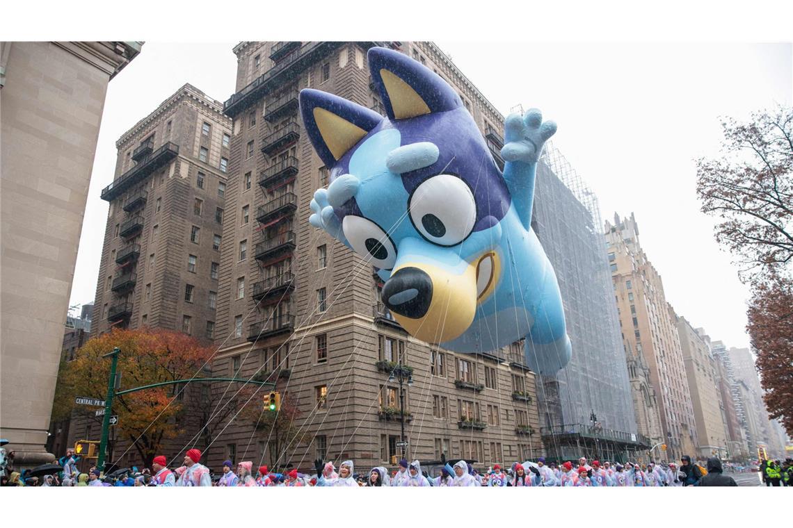 Ballons und Tanzgruppen in den Straßen New Yorks Bluey wird von vielen Mitläuferinnen und Mitläufern begleitet.