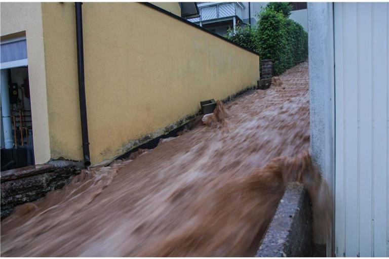 Braune Wassermassen rauschen im baden-württembergischen Altensteig über eine Treppe nach unten nach heftigen Unwettern.