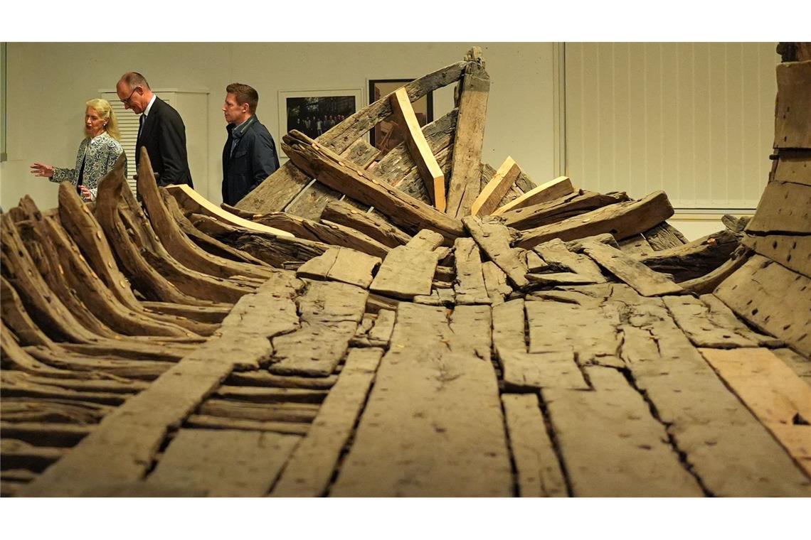 Bundeskanzler Friedrich Merz (2.v.l, CDU) geht mit Museumsdirektorin Astrid Cohrs-Dreessen (l) nach einer Pressekonferenz im Schifffahrtsmuseum Nordfriesland an dem "Zuckerschiff" vorbei.