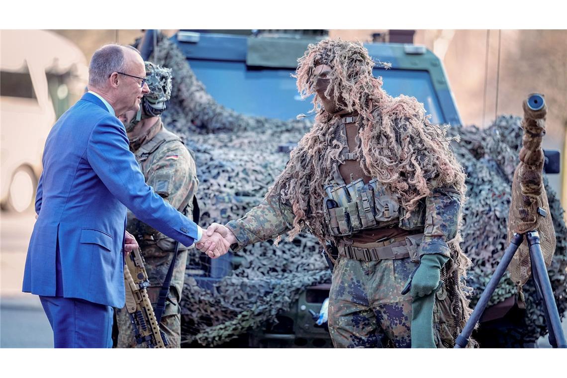 Bundeskanzler Friedrich Merz (l, CDU) wird bei der Verleihung des Fahnenbandes an das Wachbataillon in Berlin von einem Scharfschützen begrüßt.