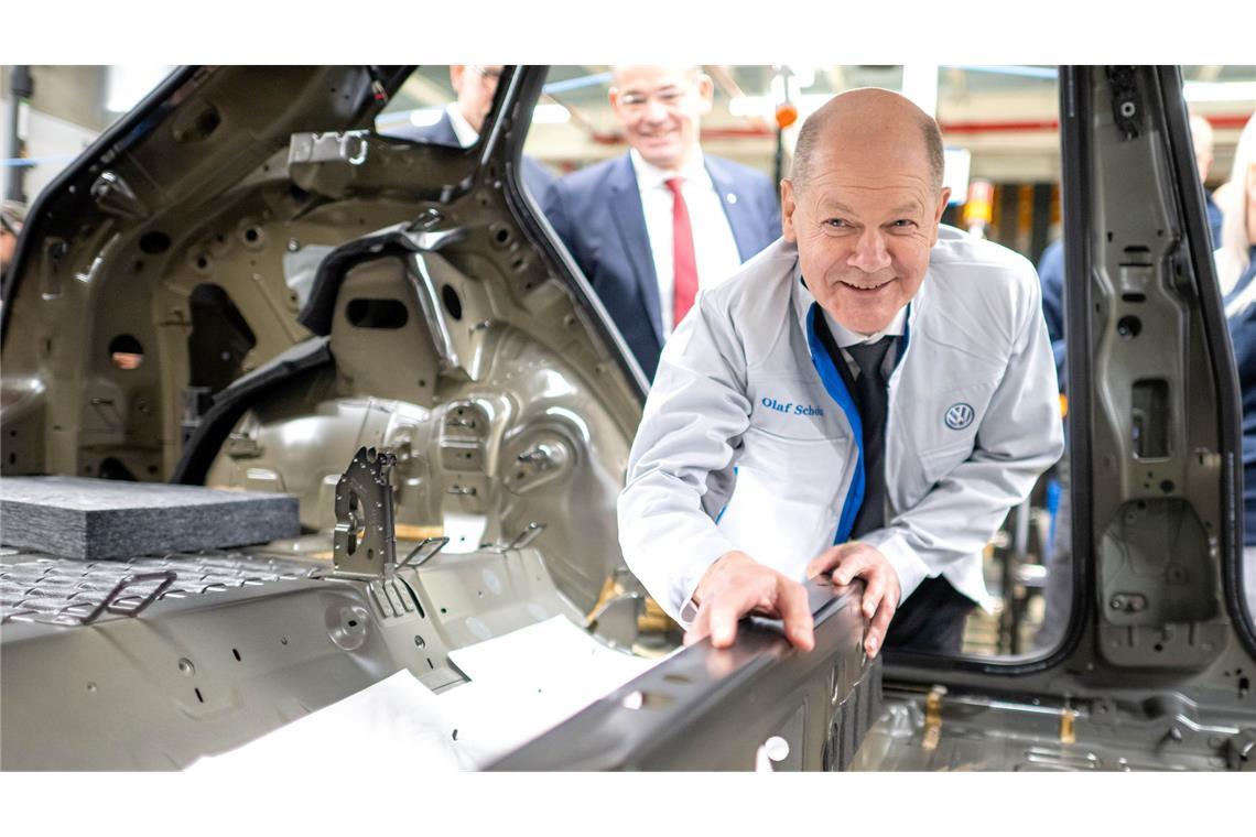 Bilder des Tages Bundeskanzler Olaf Scholz legt im VW-Werk Emden eine Dämmmatte in einen Wagen.