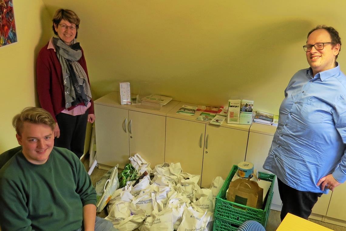 Christian Müller (rechts) und Lewin Kollak (links) haben aus den unverderblichen, verpackten Waren vom Tafelladen einige Stofftütenbündel geschnürt, sodass diese noch an Bedürftige abgegeben werden können. Birgit Wolf, Leiterin der Stelle Bürgerschaftliches Engagement, schaut kurz vorbei, ihr Arbeitsplatz ist aber einen Stock tiefer, sodass das Team auch insgesamt die Abstände wahren kann. Foto: C. Schick