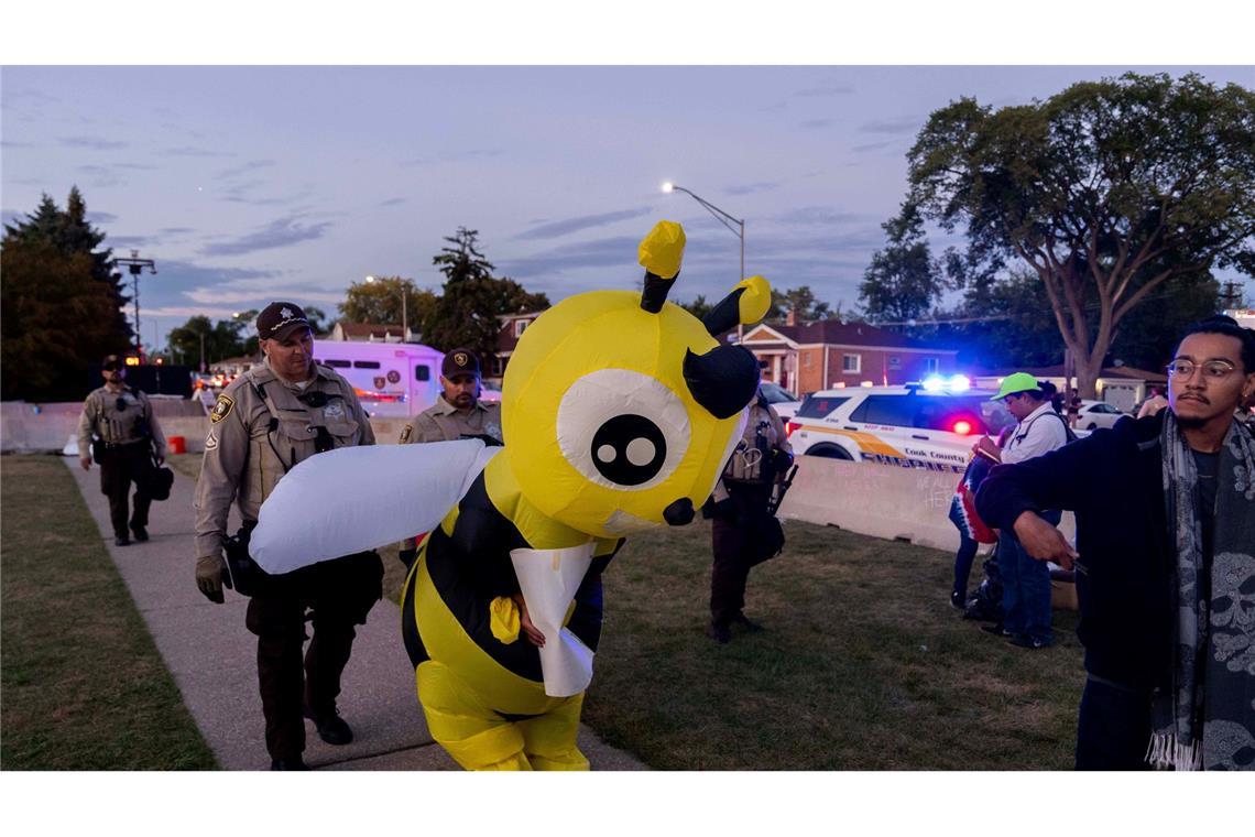 Cook County Sheriffs ziehen einen Demonstranten in einem Kostüm zurück, während sie eine Ausgangssperre vor der US-Einwanderungs- und Zollbehörde in Broadview, Illinois, durchsetzen.