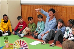 Damit es in der Kinderkonferenz ruhig ist, sodass es sich gut zuhören und erzählen lässt, gibt Iwona Kolodziejczyk (Mitte) am Anfang ein Glöckchen herum, das ganz vorsichtig und leise von Hand zu Hand wandert. Foto: Christine Schick