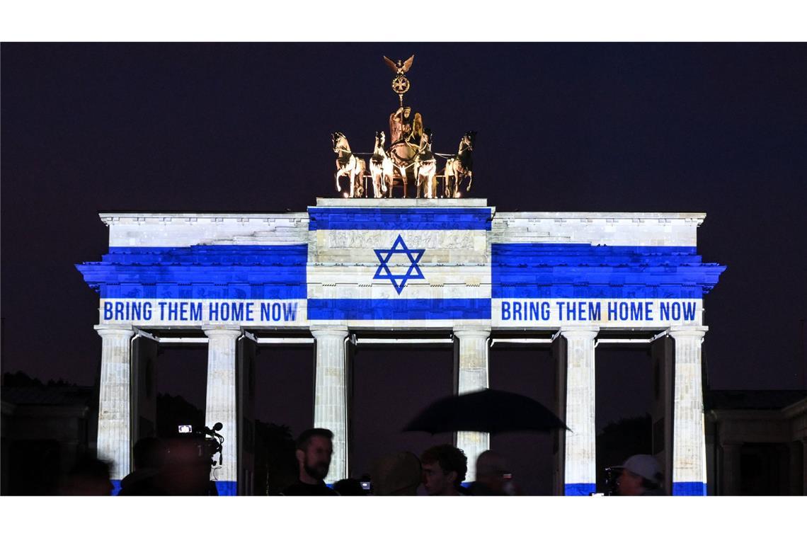 Gedenken zum 7. Oktober in Berlin: Namen der Opfer verlesen Das Brandenburger Tor ist in den Farben der israelischen Fahne angestrahlt.