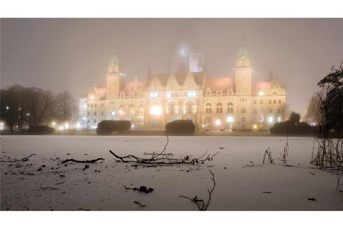 Bilder des Tages Das Neue Rathaus wird am frühen Morgen bei Nebel und Temperaturen unter dem Gefrierpunkt illuminiert, während eine dünne Eisschicht den Maschteich in Hannover bedeckt.