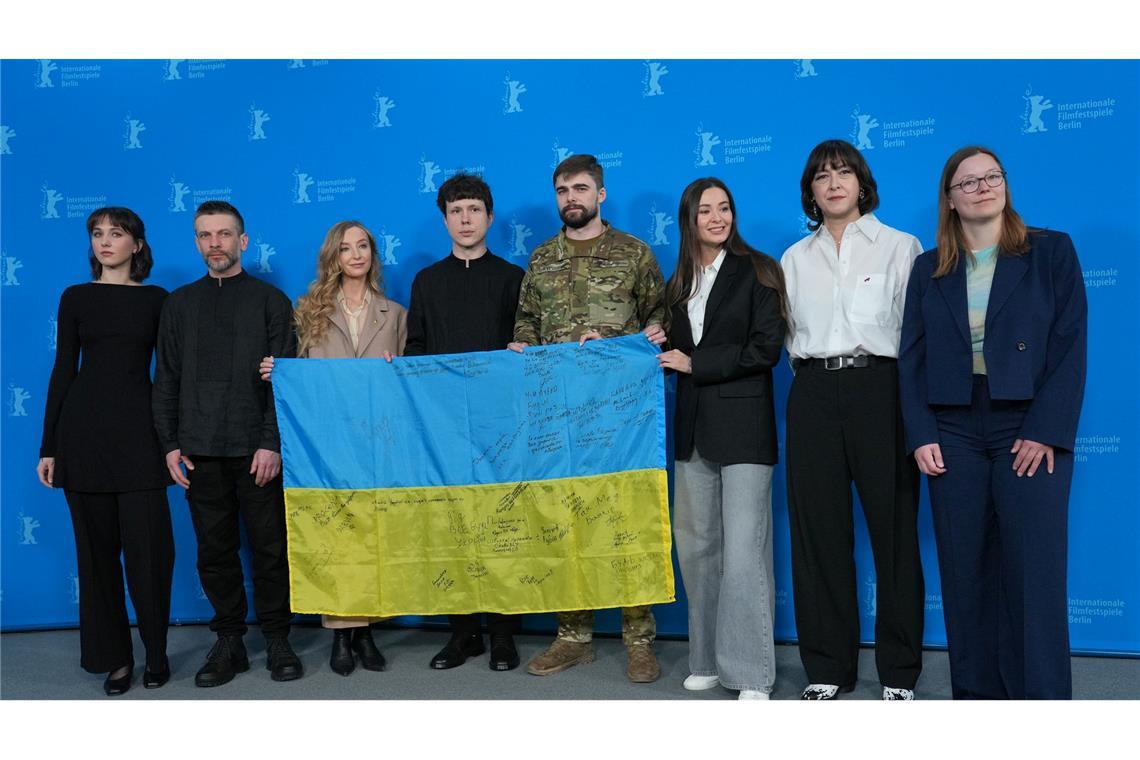 "Drømmer" gewinnt Goldenen Bären der Berlinale Das Team des Films "Strichka chasu" mit einer ukrainischen Flagge, auf der die Lehrerkollegen des Protagonisten und jetzigen Soldaten Borys Khovriak (M) unterschrieben haben.