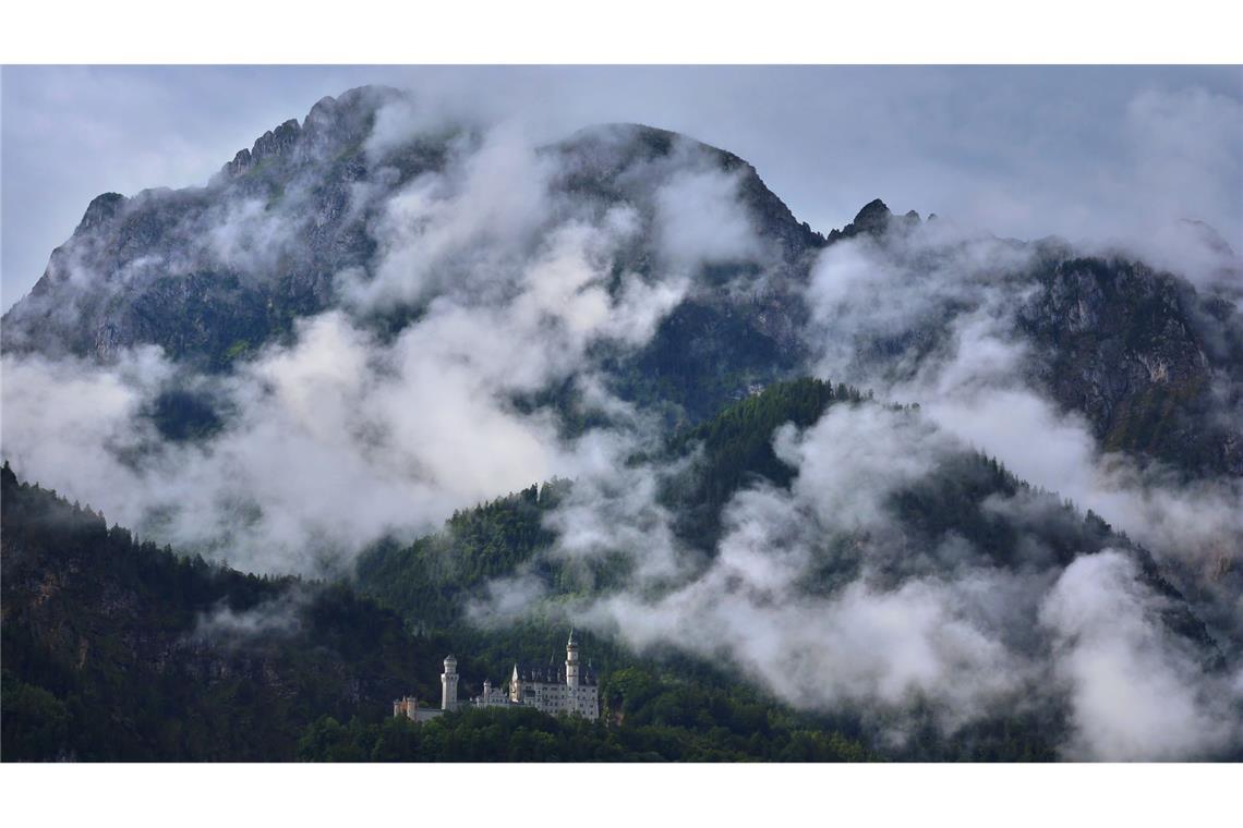Bilder des Tages Das unter Regenwolken stehende Schloss Neuschwanstein wird von der Sonne beschienen.