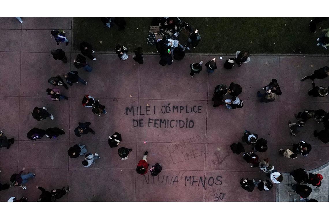 Demonstranten gehen in Buenos Aires in der Nähe eines Schriftzugs "Milei femicide accomplice" (Milei Frauenmord Mittäter), der sich auf Präsident Javier Milei bezieht, während eines Marsches zum Jahrestag der Frauenbewegung "Ni Una Menos" (Nicht eine weniger).