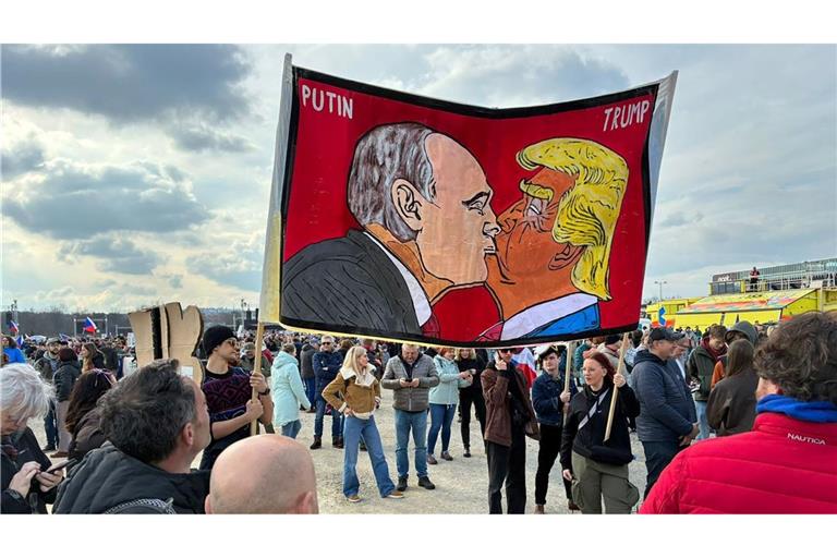 Demonstranten halten bei einer Kundgebung des Bündnisses "Eine Million Augenblicke für Demokratie" ein Banner, auf dem sich stilisiert US-Präsident Trump und Russlands Präsident Putin küssen.