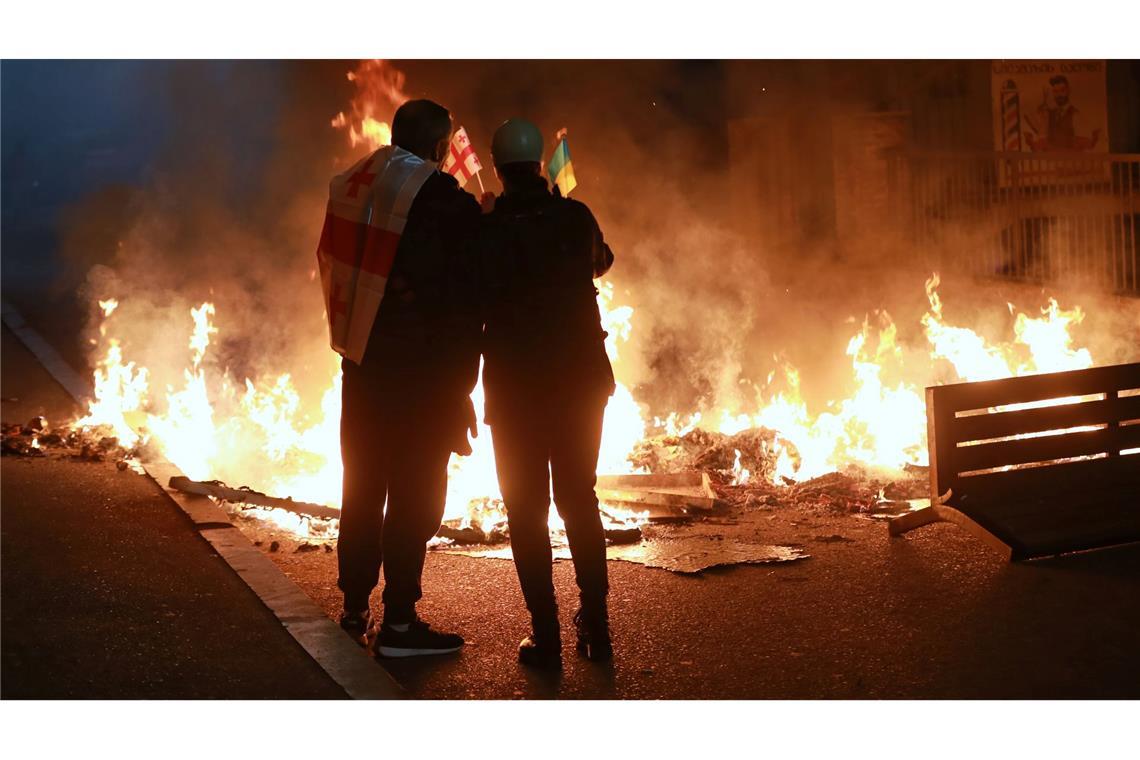 Bilder des Tages Demonstranten mit einer georgischen und einer ukrainischen Nationalflagge stehen im Stadtzentrum von Tiflis hinter einer brennenden Barrikade während einer Kundgebung der Opposition, bei der sie die Kommunalwahlen boykottieren und die Freilassung politischer Gegner fordern.
